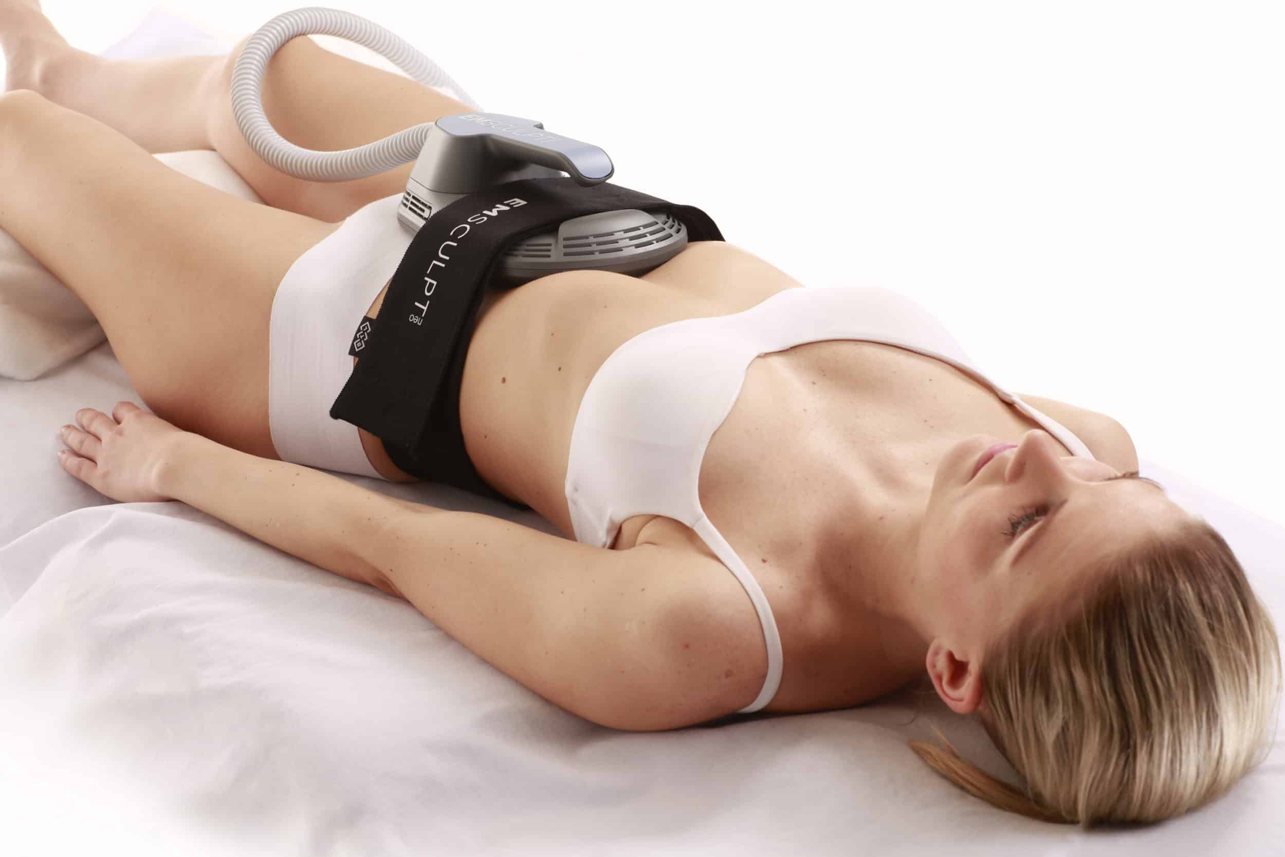 female in white underwear wearing emsculpt neo body sculpting device on stomach
