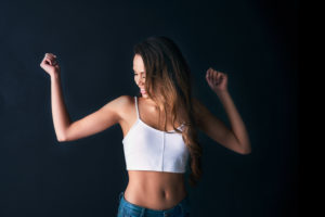 Studio shot of an attractive young woman dancing against a dark background